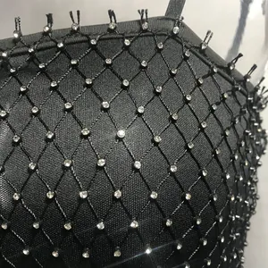 Close-up detail of black fishnet mesh with shimmering rhinestone embellishments on dress.