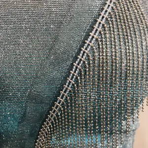 Détail d'un haut métallique scintillant avec d'élégantes franges à perles dorées