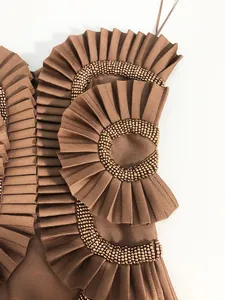 Detailed macro shot of brown bandage dress with pleated ruffles and intricate beadwork