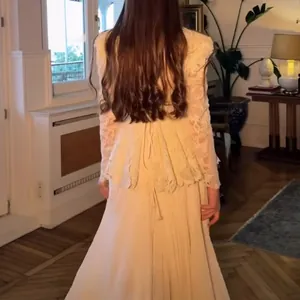 Back view of elegant cream lace two-piece set with long sleeves and flowing skirt