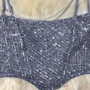 Close-up detail of a silver sequined corset top featuring pearl and metal chain accents.