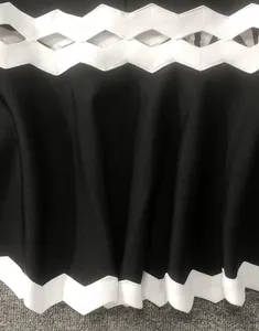 Dettaglio abito a fascia nero con finiture smerlate bianche e design con cut-out