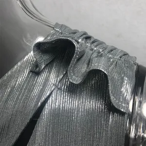 Primer plano del detalle de volantes en el hombro de un vestido plateado brillante.
