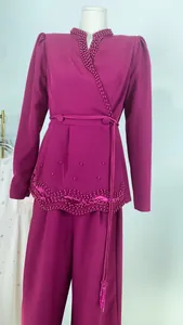 Détail du haut fuchsia à manches longues orné de perles et de l'ensemble pantalon large assorti