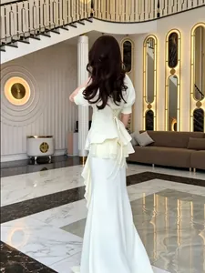 Elegant cream white peplum fishtail evening gown showing detailed back lacing and tiers.