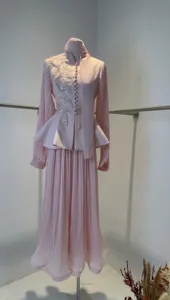 Detailed view of an elegant pink pleated skirt suit featuring floral embroidery and mesh sleeves.