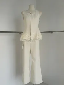 Detailed view of cream sleeveless top with lace hem and matching wide-leg trousers