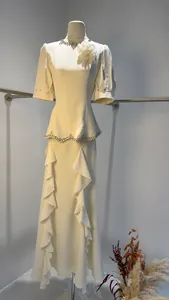 Elegant white evening dress with beaded neckline and ruffled fishtail skirt on mannequin.