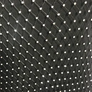 Detailed close-up view of black mesh fabric featuring sparkling rhinestone embellishments