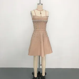 Elegant beige evening dress featuring heavy rhinestone and pearl embellishments on mannequin
