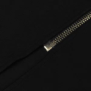 High-quality golden metal zipper detail on black bandage dress with textured fabric.