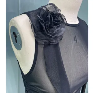Close-up detail of the elegant 3D fabric flower on a sexy black mesh sleeveless dress.