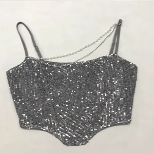 Detailed view of silver sequined camisole with pearl and chain strap decoration.