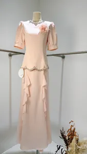 Detail of an elegant pink peplum maxi dress featuring a beaded neckline and ruffles