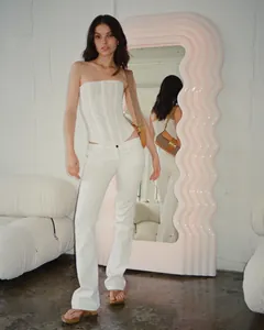 Detailed view of a white mesh strapless corset top paired with white pants in a studio setting