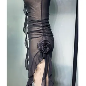 Close-up of black mesh dress with 3D floral accent and elegant side ruffles.