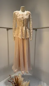 Detail of elegant beige lace peplum top and matching pleated maxi skirt set for women