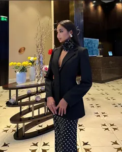 Elegant women's black blazer paired with polka dot skirt and a large flower choker accessory