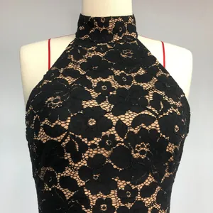 Detailed macro view of black floral lace fabric on a stylish halter neck mini dress