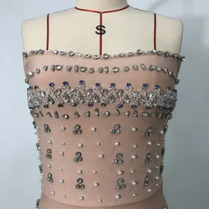 Close-up view of heavy rhinestone and pearl details on a nude bandage tube dress