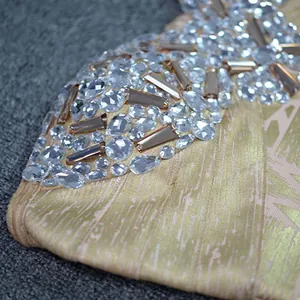 Detailed macro view of sparkling clear rhinestones and metallic gold foil on bandage dress