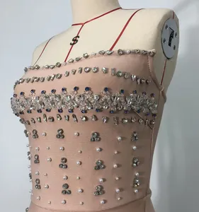 Close-up of elegant nude bandage dress with heavy rhinestone and pearl details