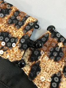 Detail shot of leopard print dress featuring sequins and black round button closure