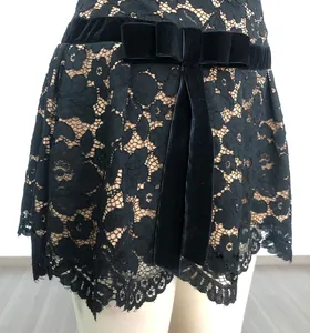 Close-up of black floral lace mini skirt with velvet bow belt and eyelash lace hem