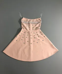 Detailed view of heavy rhinestone and pearl embellishments on a peach cocktail dress.