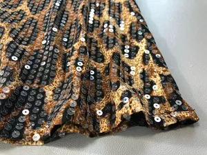 Macro view of leopard print dress fabric featuring shimmering silver sequin stripes