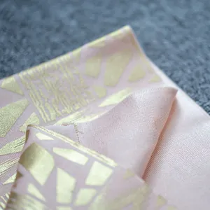 Macro detail of luxury pink fabric with gold foil geometric patterns for a bandage dress.