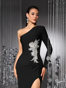 Detail view of a black one-shoulder evening dress with silver rhinestone floral applique
