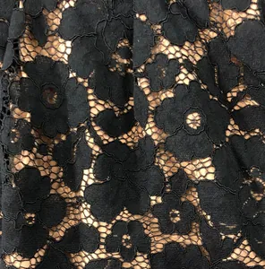 Detailed macro shot of elegant black floral lace fabric texture on a beige lining base