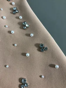 Detailed shot of pearls and rhinestones on high-quality bandage evening dress fabric.