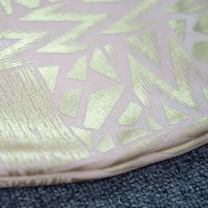 Close-up detail of luxurious gold stamping pattern on pink bandage dress fabric