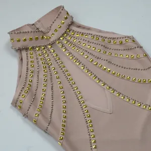 Dettaglio di borchie dorate e perline argentate su abito a fascia rosa con scollo