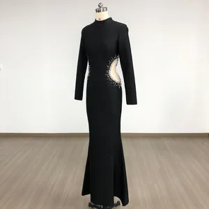 Full view of elegant black long-sleeved evening gown with sparkling rhinestone cut-outs.
