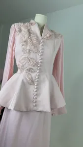 Close-up of elegant pink blazer set with sequin floral appliqué and pleated sleeves.