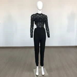 Black long-sleeved mesh jumpsuit with silver beads and cut-out waist detail on mannequin.