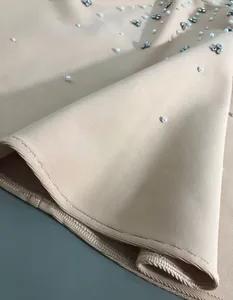 Detailed view of bandage fabric with delicate pearl and rhinestone embellishments on a dress