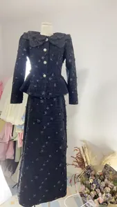 Detailansicht eines schwarzen Tweed-Zweiteilers mit 3D-Blumenapplikationen und Spitzenkragen