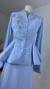 Detail of light blue suit with sequined leaf embroidery and pleated sleeves