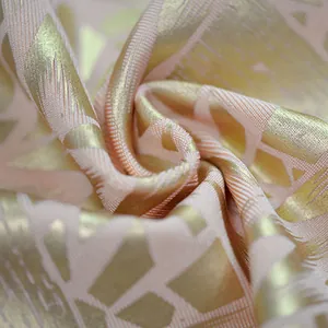 Detail macro shot of luxury pink fabric with gold foil geometric pattern for party dress.