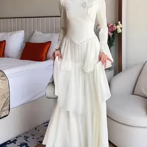 Elegant white long sleeve tiered dress with floral applique detail in a bedroom setting