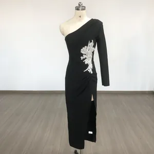 Detailed view of black one-shoulder bandage dress with beaded flower accent and side slit