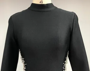Close-up detail of a slim black bandage evening dress with side rhinestone accents