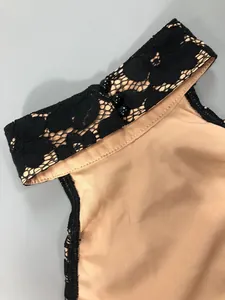 Detailed view of black floral lace collar and beads on a sexy nude mini halter dress.
