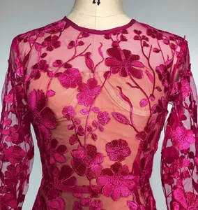 Detailed macro view of elegant fuchsia floral embroidery on long sleeve lace dress