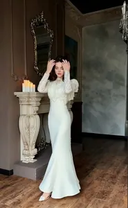 Elegant white lace long sleeve fishtail evening gown shown in a vintage interior