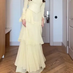 Elegant pale yellow tiered chiffon maxi dress with long sleeves and delicate waist detailing